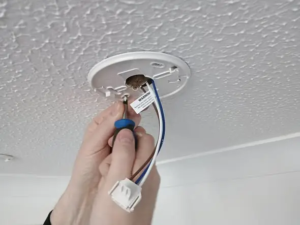 Engineer inspecting a ceiling-mounted fire alarm device